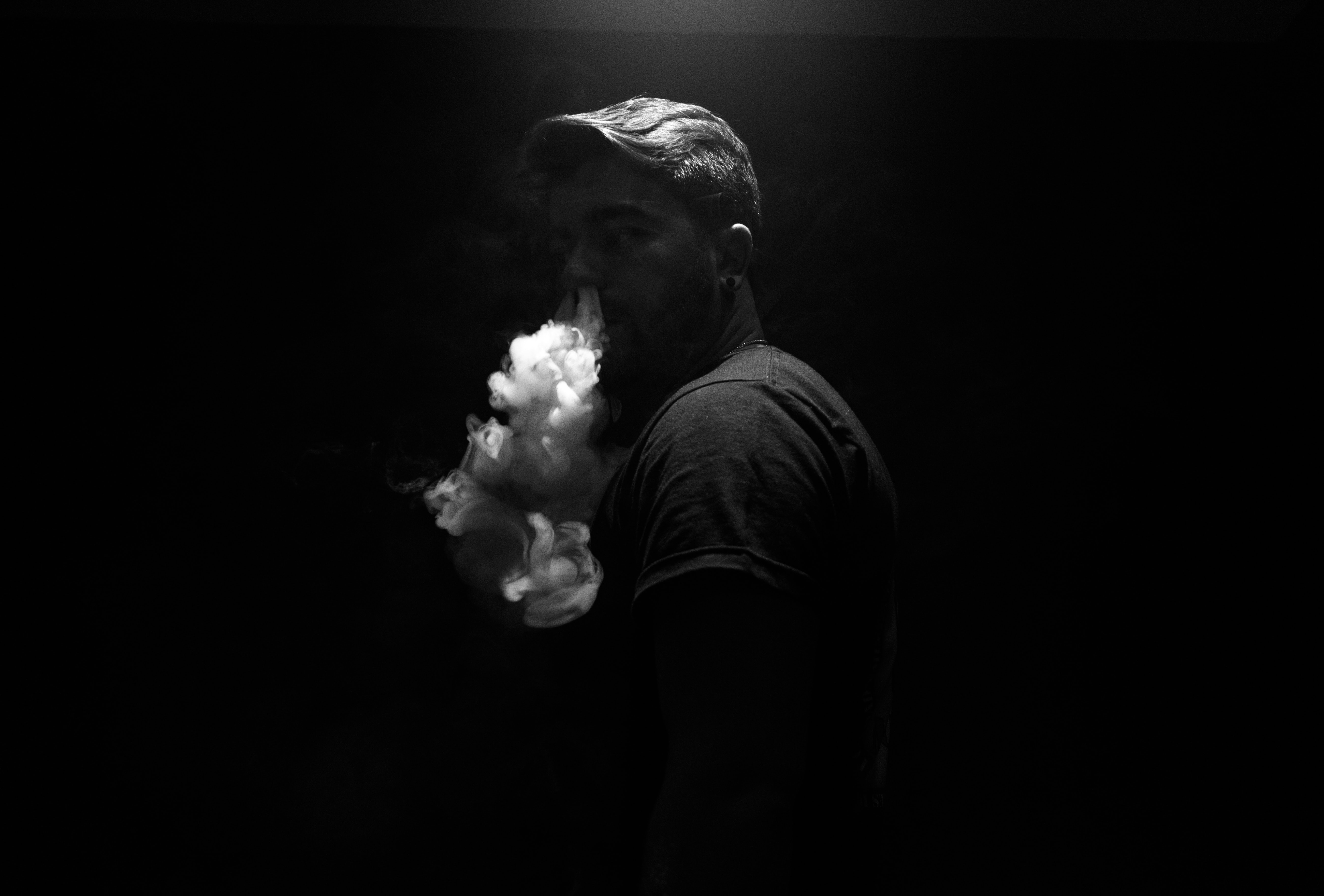 grayscale photo of man exhaling smoke