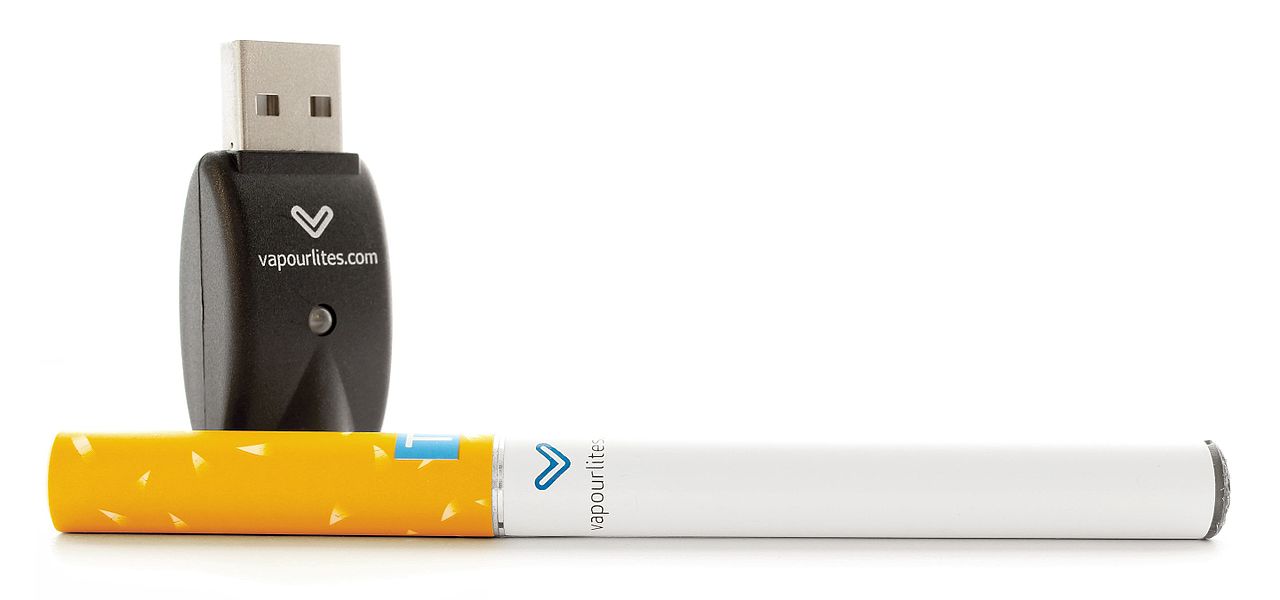 A first-generation e-cigarette that resembles a tobacco cigarette. Also shown is a USB power charger, which the battery portion of the e-cigarette can be disconnected and recharged with.